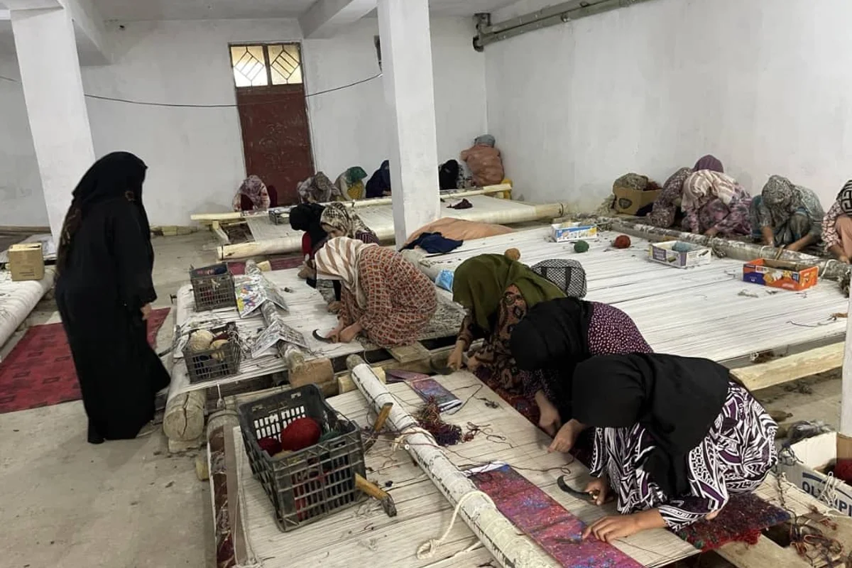 Afghan women working together at carpet looms in a workshop